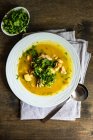 Sopa de pollo saludable con verdura y hierba de cilantro servida en un tazón sobre una mesa de madera - foto de stock