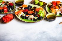 Sushi Set  with various sashimi, sushi rolls and tea  served on stone slate — Stock Photo
