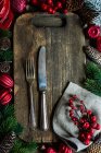 Tabla de cortar de madera vintage y cubiertos con decoración festiva como concepto de vacaciones de Navidad - foto de stock