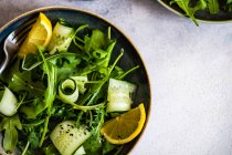 Здоровий овочевий салат з арагулою, авокадо та насінням кунжуту на бетонному фоні з місцем для тексту — стокове фото