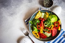 Здоровий овочевий салат з арагулою, авокадо та насінням кунжуту на бетонному фоні з місцем для тексту — стокове фото