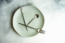 Intermittierendes Fastenkonzept mit Teller und Besteck mit Uhr und Essenszeit — Stockfoto