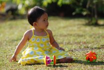Girl sitting in a park playing with toys, Indonesia — Stock Photo