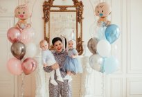 Ritratto di una donna sorridente che tiene in braccio i suoi nipoti gemelli al loro primo compleanno — Foto stock