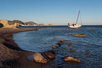 Boat chanchored by beach at low tide, Los Escullos beach, Los Escullos, Cabo de Gata, Almeria, Andalusia, Spain — стокове фото