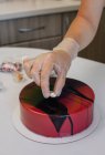 Mujer decorando un pastel de chocolate de terciopelo rojo hecho en casa - foto de stock
