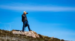 Hombre de pie sobre una roca tomando una foto, Highlands, Escocia, Reino Unido - foto de stock