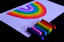 Rainbow drawing and multi coloured crayons — Stock Photo