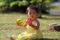 Chica sentada en un parque jugando con juguetes, Indonesia - foto de stock