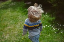 Visão traseira de um menino correndo em um jardim — Fotografia de Stock