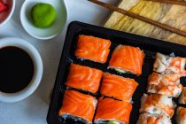 Leckeres Sushi mit Sojasauce auf Holzteller — Stockfoto