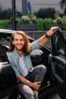 Портрет улыбающегося мужчины, сидящего в машине и ожидающего с открытой дверью — стоковое фото