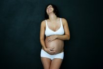 Pregnant woman in her underwear cradling her bump — Stock Photo