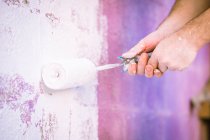 Close-up of a man painting a wall with a paint roller — Stock Photo