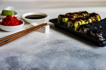 Rolos de sushi maki com gengibre em conserva, wasabi, molho de soja e pauzinhos — Fotografia de Stock