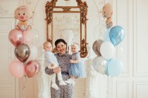 Retrato de uma mulher sorridente segurando seus netos gêmeos em seu primeiro aniversário — Fotografia de Stock