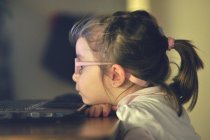 Menina sentada em uma mesa olhando para uma tela de computador — Fotografia de Stock