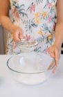 Mujer de pie en la cocina tamizar harina en un tazón - foto de stock