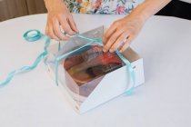 Woman packing home made cake in a gift box — Stock Photo