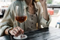 Femme assise à une table dégustant un verre de vin rose — Photo de stock