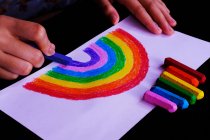 Bambino che disegna arcobaleno con pastelli — Foto stock