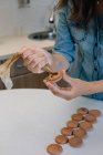 Жінка наповнює шоколадні макаруни шоколадною ганачею — стокове фото