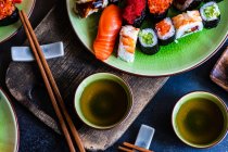 Plates of assorted maki sushi rolls and nigiri sushi on a table — Stock Photo
