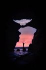 View from a cave of a man standing on a rock in the sea, Iceland — Stock Photo