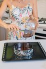 Mulher derramando massa bolo em uma lata de bolo — Fotografia de Stock
