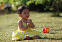 Ragazza seduta in un parco a giocare con i giocattoli, Indonesia — Foto stock