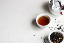 Taza de té con hojas de té y una tetera - foto de stock