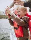 Boy standing on a boat holding a freshly caught fish, USA — Stock Photo