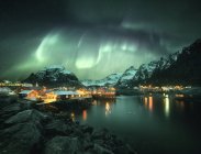 Luces boreales sobre un pueblo costero, Lofoten, Nordland, Noruega - foto de stock