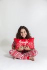 Portrait of a happy girl in pyjamas holding a Christmas pillow — Stock Photo
