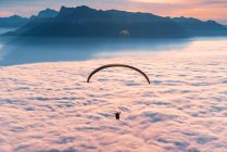 Silhueta de um Parapente voando acima do tapete de nuvens ao pôr do sol, Gaisberg, Salzburgo, Áustria — Fotografia de Stock