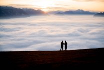 Silhouette de deux femmes sur un sommet de montagne au coucher du soleil regardant la vue, Salzbourg, Autriche — Photo de stock