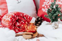 Galletas de Navidad, vela y árbol de Navidad en miniatura junto a almohadas y una alfombra - foto de stock