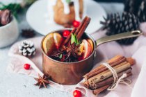 Primo piano di vin brulè in una casseruola di rame accanto a una torta di Natale con mirtilli rossi — Foto stock