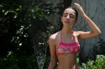 Девочка-подросток, стоящая в саду и охлаждающаяся из водяного шланга, Аргентина — стоковое фото