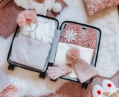 Открытый чемодан с одеждой, дорожными принадлежностями и плюшевым мишкой — стоковое фото