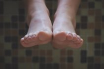 Primer plano de los pies de una chica colgando sobre el borde de un baño - foto de stock