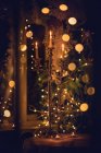 Candlestick on a table in front of a Christmas tree — Stock Photo