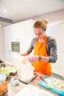 Женщина, стоящая на кухне и взвешивающая муку — стоковое фото