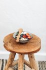 Миска муслі зі свіжими ягодами на дерев'яному табуреті — стокове фото