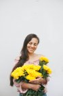 Mulher sorridente segurando um buquê de crisântemos amarelos — Fotografia de Stock