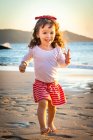 Souriante fille courant sur la plage avec une poignée de sable, Brésil — Photo de stock