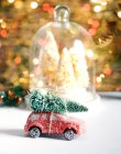 Weihnachtsdekoration in einem gewölbten Tablett neben einem Spielzeugauto mit einem Weihnachtsbaum auf dem Dach — Stockfoto