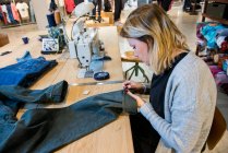 Couturière ajustant une paire de jeans dans son studio — Photo de stock