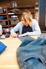 Costurera ajustando un par de jeans en su estudio - foto de stock