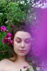 Porträt einer Frau, die in einem Garten neben süßen Erbsenblumen steht, England, UK — Stockfoto